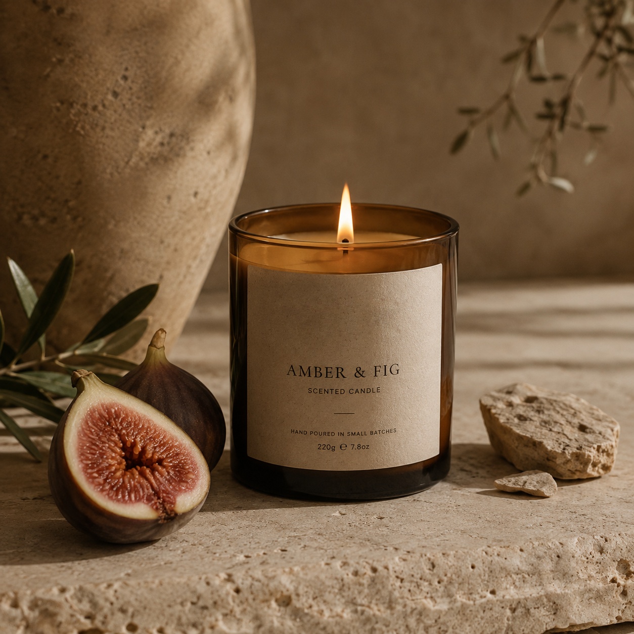 An Amber & Fig scented candle styled with fresh figs and olive branches